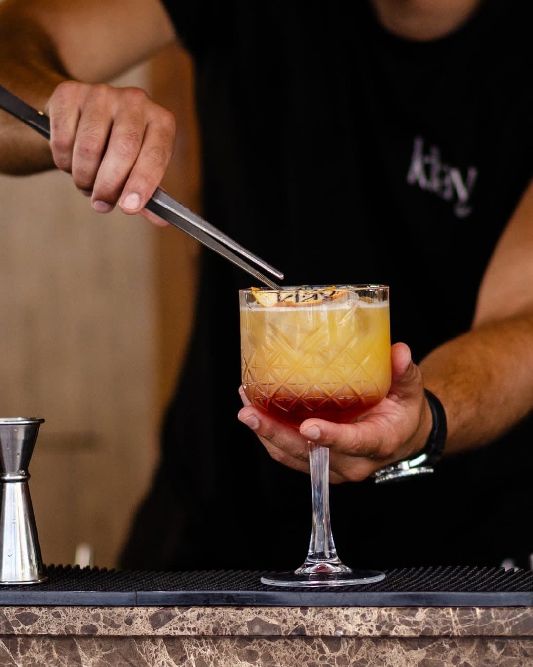 A Klay bartender finishing a cocktail with tweezers