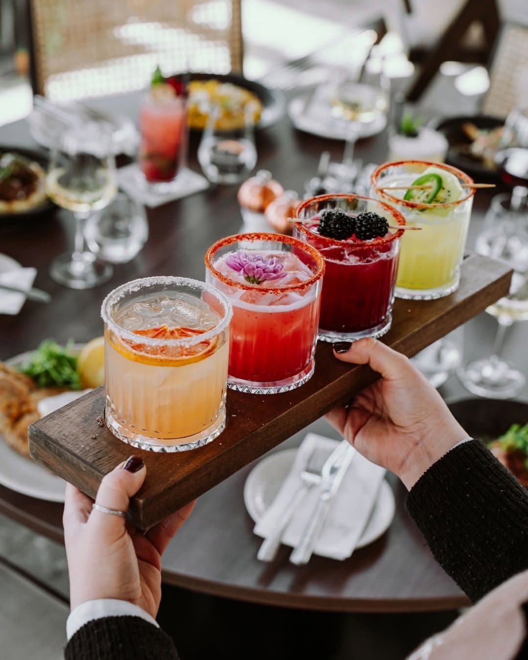 A wooden board of four colourful house cocktails